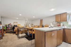 Kitchen with brown cabinetry, light countertops, recessed lighting, and a peninsula
