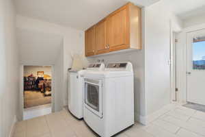 Laundry area featuring baseboards, light tile patterned flooring, independent washer and dryer, and cabinet space