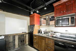 Kitchen featuring track lighting, reddish brown cabinets, a sink, and black appliances