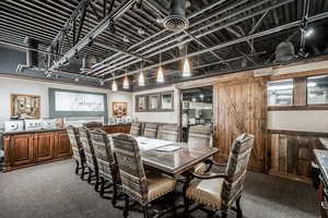Carpeted dining space featuring wood walls