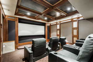 Carpeted home theater with coffered ceiling and beam ceiling
