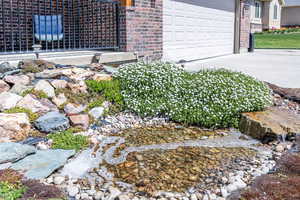 Details featuring brick siding, driveway, and a small pond