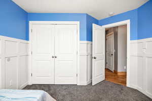Bedroom with wainscoting, carpet, and a closet