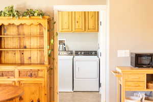 Clothes washing area featuring washing machine and dryer and light tile patterned floors