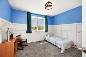 Bedroom with wainscoting, a decorative wall, visible vents, and carpet floors