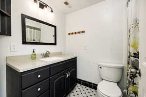Bathroom with baseboards, visible vents, vanity, and toilet