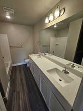 Full bathroom featuring a textured ceiling, visible vents, baseboards, and a sink