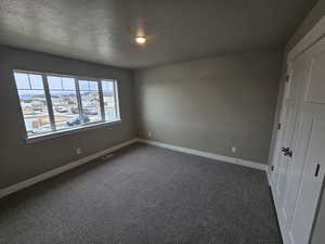 Interior space featuring dark carpet, baseboards, and visible vents