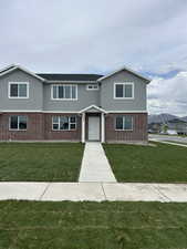 View of front of property featuring stucco siding, a front lawn, and brick siding