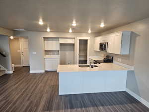 Kitchen with a peninsula, light countertops, appliances with stainless steel finishes, and baseboards