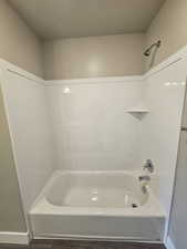 Full bathroom featuring bathtub / shower combination, baseboards, and a textured ceiling
