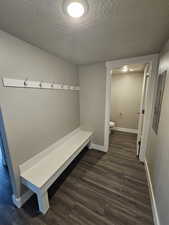 Mudroom featuring electric panel, baseboards, a textured ceiling, and dark wood finished floors