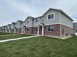 View of property featuring brick siding, central air condition unit, and a front yard