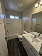 Full bathroom featuring shower / bathtub combination, wood finished floors, toilet, visible vents, and a textured ceiling