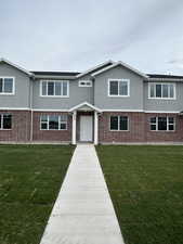 View of front of property with stucco siding, brick siding, and a front yard