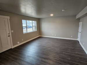 Interior space with baseboards, a textured ceiling, and dark wood-style floors