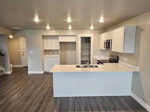 Kitchen with a peninsula, light countertops, appliances with stainless steel finishes, and baseboards