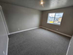 Spare room with baseboards, a textured ceiling, visible vents, and carpet