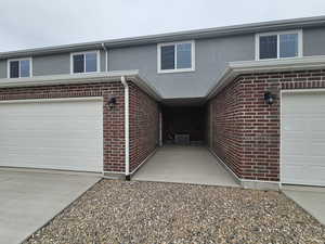 View of front of property featuring brick siding, central AC, a garage, and stucco siding