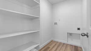 Washroom with electric dryer hookup, light wood finished floors, baseboards, laundry area, and washer hookup