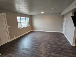 Interior space featuring recessed lighting, baseboards, a textured ceiling, and dark wood-type flooring