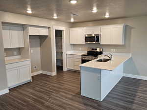 Kitchen featuring a peninsula, baseboards, appliances with stainless steel finishes, and white cabinets