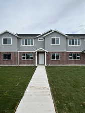 View of front of home featuring stucco siding, brick siding, and a front yard
