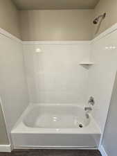 Full bath featuring a textured ceiling, baseboards, and shower / tub combination