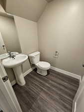 Bathroom with a sink, toilet, baseboards, lofted ceiling, and wood finished floors