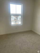 Carpeted spare room featuring baseboards
