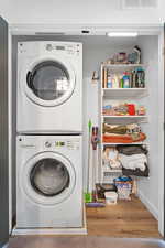 Laundry room with stacked washer / drying machine and wood finished floors