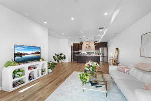 Living area with light wood finished floors and recessed lighting