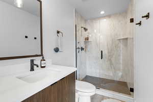Bathroom featuring a marble finish shower and vanity