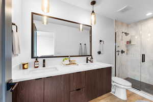 Full bath featuring double vanity, a stall shower, wood finished floors, and recessed lighting