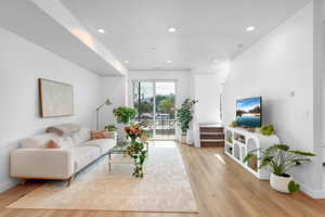 Living room featuring light wood-style flooring, recessed lighting, and stairs