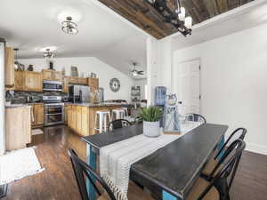 Dining space featuring baseboards, lofted ceiling, dark wood-style floors, and ceiling fan