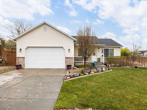 Ranch-style house with fence, driveway, a front yard, and a garage