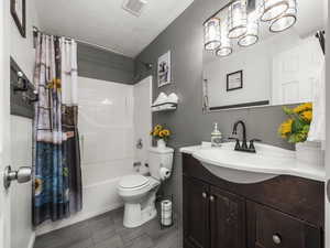 Bathroom featuring wood finished floors, vanity, shower / tub combo with curtain, toilet, and visible vents