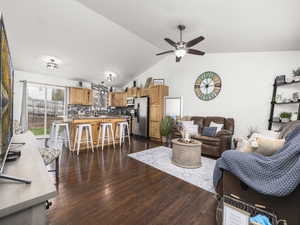Living area featuring ceiling fan, vaulted ceiling, and dark wood-style flooring