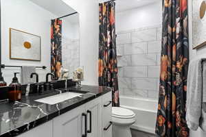 Full bathroom with tile patterned flooring, toilet, vanity, and shower / bath combo with shower curtain