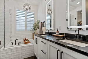 Bathroom with a bath, a notable chandelier, and a sink