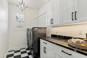 Laundry room featuring washing machine and dryer, tile patterned floors, baseboards, and cabinet space