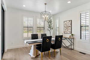 Dining room featuring baseboards, an inviting chandelier, visible vents, and light wood-type flooring