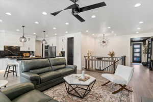 Living area featuring light wood-type flooring, a ceiling fan, baseboards, and recessed lighting