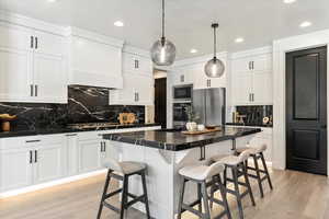 Kitchen with recessed lighting, backsplash, dark countertops, appliances with stainless steel finishes, and white cabinetry
