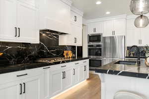 Kitchen with a sink, decorative backsplash, white cabinets, appliances with stainless steel finishes, and recessed lighting