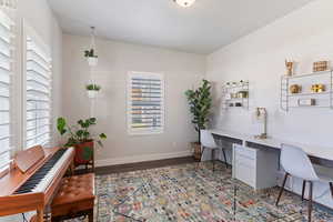 Office area featuring baseboards, wood finished floors, and built in study area