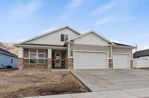 Craftsman-style house featuring central air condition unit, concrete driveway, an attached garage, board and batten siding, and stone siding