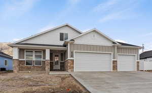Craftsman inspired home featuring a garage, stone siding, concrete driveway, and board and batten siding