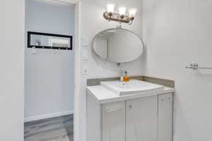Bathroom featuring baseboards, wood finished floors, and vanity